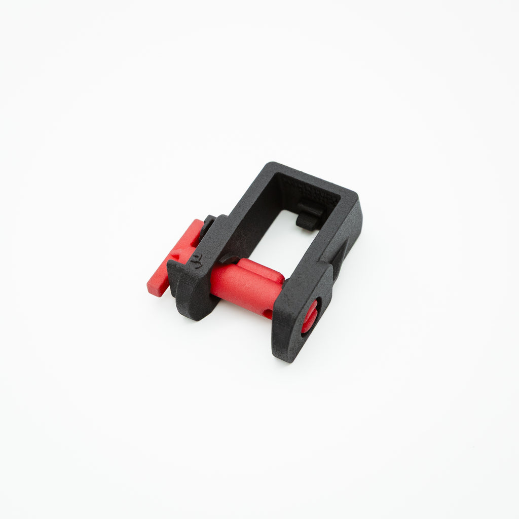 A small black plastic clamp-like component with red internal and external parts, shown on a clean white background.