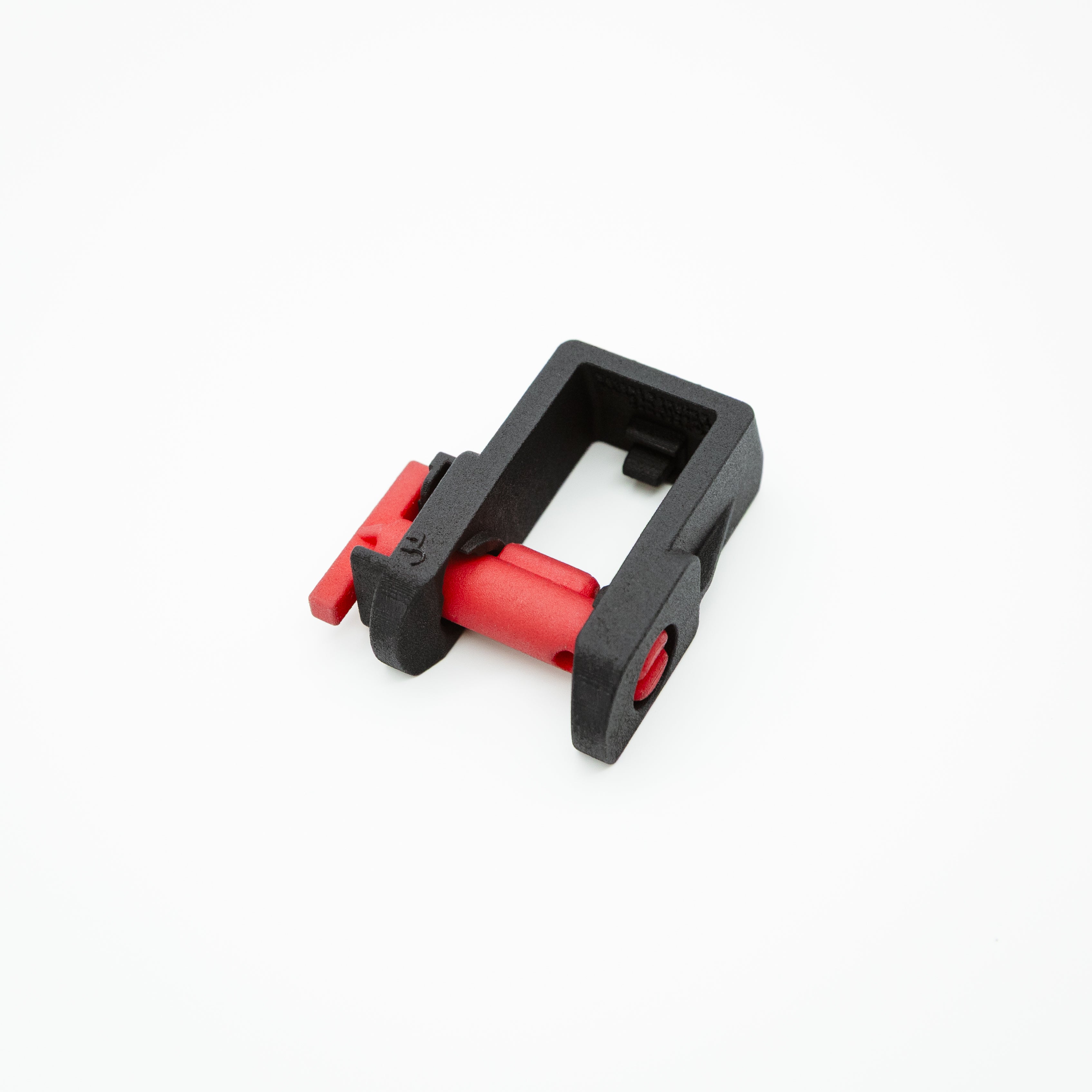 A small black plastic clamp-like component with red internal and external parts, shown on a clean white background.